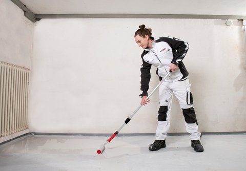 ISOTEC Mitarbeiter verteilt graue Flüssigkeit auf Kellerboden